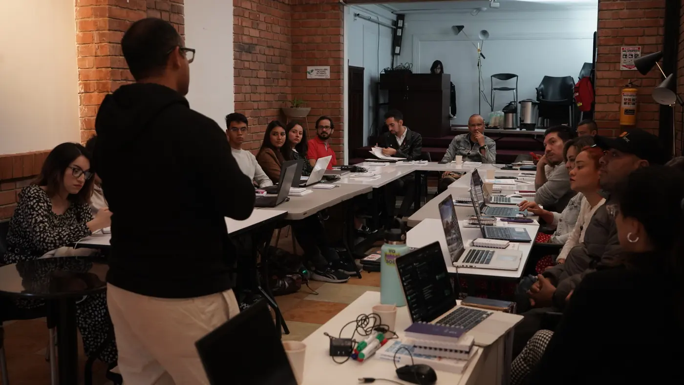 Un capacitador habla frente a un equipo con portátiles