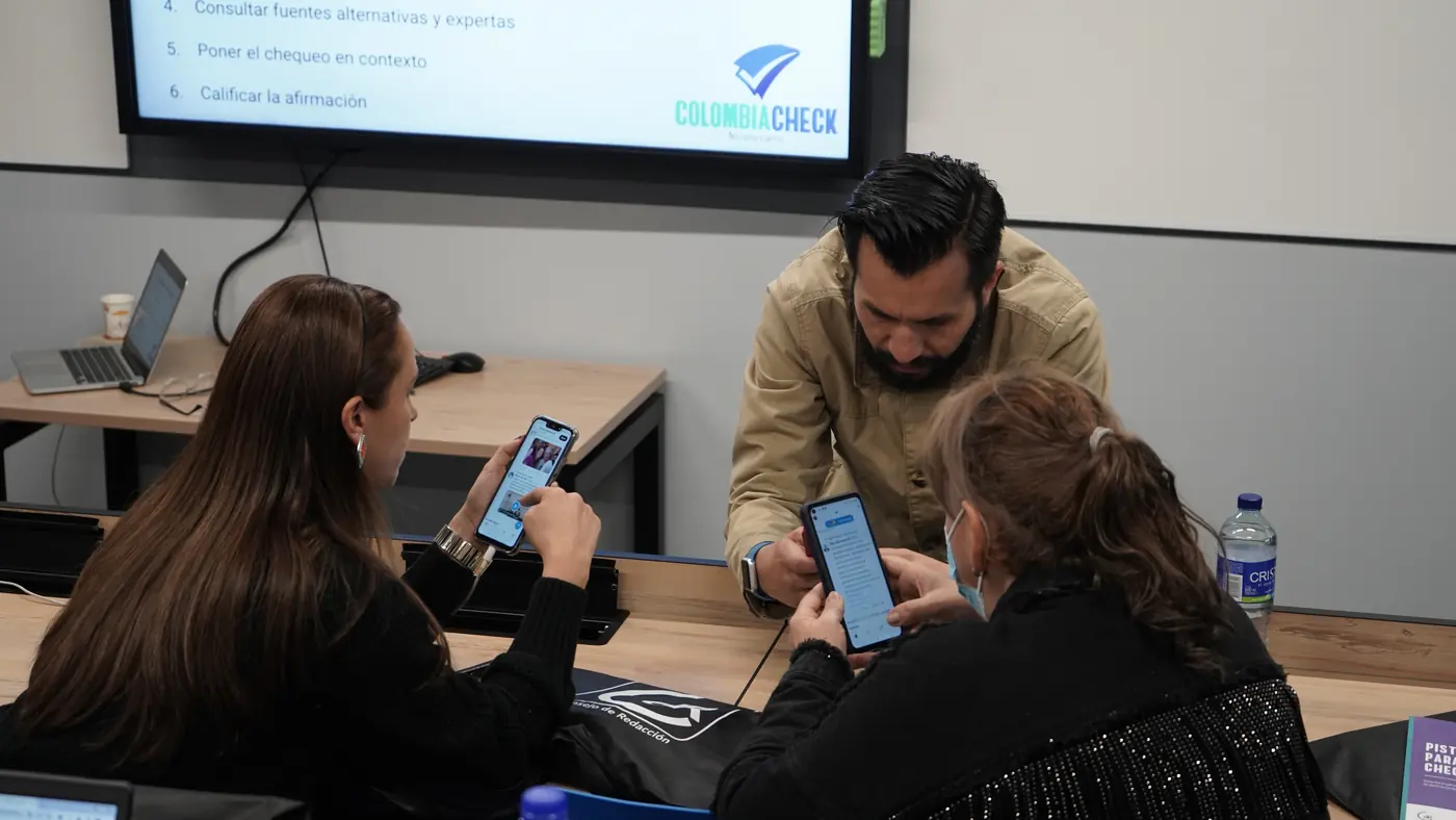 Participantes revisan contenidos en sus celulares con ayuda de un formador