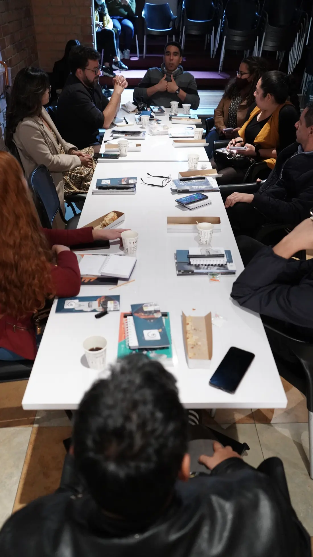 Participantes de un taller de Colombiacheck alrededor de una mesa larga con materiales de trabajo